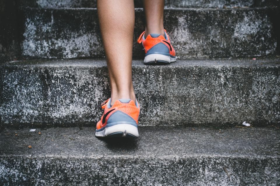 Person climbing steps in orange running shoes