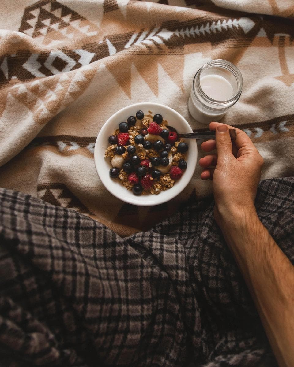 Tazón de granola con frutos rojos sostenido en el regazo