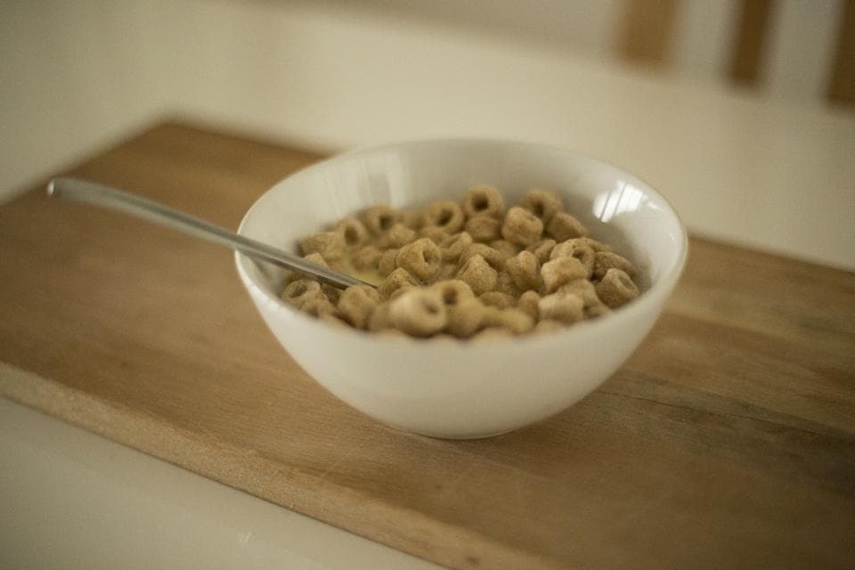 Tazón de cereal con cuchara sobre una mesa de madera